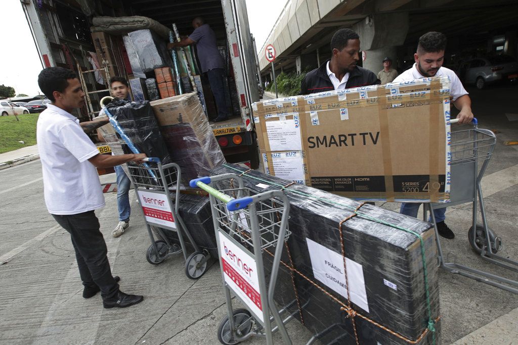 Trabajadores descargan el equipaje de doctores cubanos en el aeropuerto mientras se preparan para volar a casa en Brasilia, Brasil, el jueves 22 de noviembre de 2018. (AP Foto/Eraldo Peres)