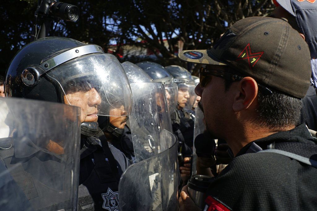 La policía protege un albergue de migrantes centroamericanos de manifestantes que protestan por su presencia, en Tijuana, México, el domingo 18 de noviembre de 2018. (AP Foto/Ramón Espinosa)
