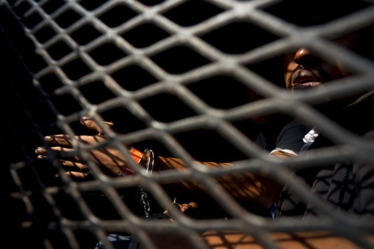 Un hombre que es parte de la caravana de migrantes centroamericanos, dentro de una camioneta de la policía después de ser arrestado, de acuerdo a las autoridades, por fumar marihuana, en Tijuana, México, el miércoles 21 de noviembre de 2018. Foto: Ramon Espinosa / AP.