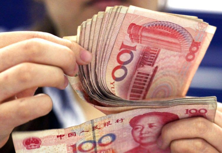 En esta foto del 25 de agosto de 2010, un cajero bancario cuenta billetes de 100 yuan en Shanghái. La moneda china cayó a su nivel más bajo en 22 meses frente al dólar, se informó el jueves 18 de octubre de 2018. (AP Foto/Eugene Hoshiko)