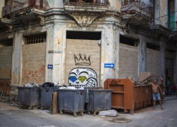 En esta foto del 22 de octubre de 2018, un hombre arroja basura en un contenedor en La Habana Vieja, Cuba.  (AP Foto AP / Desmond Boylan)