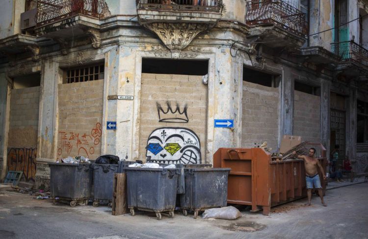 En esta foto del 22 de octubre de 2018, un hombre arroja basura en un contenedor en La Habana Vieja, Cuba.  (AP Foto AP / Desmond Boylan)