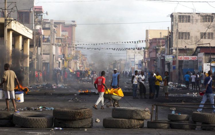 Residentes caminan entre las calles bloqueadas por manifestantes en contra del gobierno en el Boulevard Jean-Jacques Dessalines, una de las principales avenidas comerciales, durante una huelga anti gubernamental el miércoles 21 de noviembre de 2018 en Puerto Príncipe, Haití. Foto: Dieu Nalio Chery / AP.