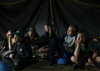 Niños que participan en un campamento de elementos nacionalistas de Ucrania con sus fusiles a su lado escuchan a un instructor el 28 de julio de 2018. En los campamentos les inculcan una ideología nacionalista y les enseñan a combatir a los rusos y sus partidarios. Foto: Felipe Dana / AP.