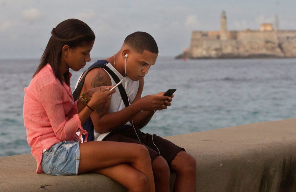 Una pareja de jóvenes se conecta a internet desde el malecón, el 27 de diciembre de 2018, en La Habana. Foto: Yander Zamora / EFE.