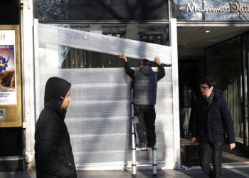 Un hombre protege el escaparate de una tienda en los Campos Elíseos, en París, el 14 de diciembre de 2018. Foto: Francois Mori / AP.