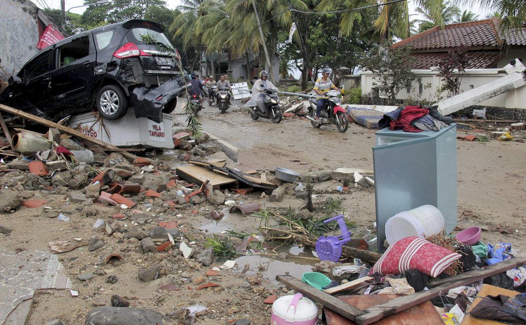 Varios motociclistas avanzan por una calle llena de escombros tras el paso de un tsunami en Anyar, Indonesia, el domingo 23 de diciembre de 23, 2018. Foto: AP.