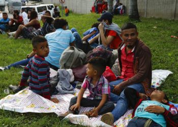 Freddy Rivas (segundo por la derecha), natural de Tocoa, Honduras, sus hijos Josué (izquierda) y Elkin (centro) y su hermano Mario esperan la llegada de más migrantes a una caravana que viajará hacia la frontera de Estados Unidos, en San Pedro Sula, Honduras, el 14 de enero de 2019. (AP Foto/Delmer Martinez)