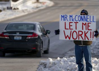 Un trabajador de la Agencia de Protección Ambiental de EEUU (EPA, por sus siglas en inglés) afectado por el cierre parcial del gobierno protesta con un cartel ante las oficinas del senador Mitch McConnell, en Park Hills, Kentucky, el 22 de enero de 2019. Foto: Bryan Woolston / AP.