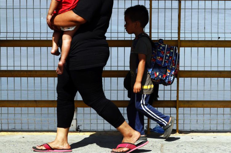 Una madre y sus dos hijos caminan sobre el puente del río Suchiate, parte de un grupo de migrantes centroamericanos que cruzaron la frontera entre Guatemala y México, cerca de Ciudad Hidalgo, estado de Chiapas, México, el jueves 17 de enero de 2019. (AP Foto/Marco Ugarte)