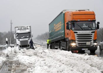 Dos camioneros se ayudan después de haber quedado atrapados por una fuerte nevada en la autopista A8 cerca de Holzkirchen, en el sur de Alemania, el lunes 7 de enero de 2019. Foto: Tobias Hase / dpa vía AP.