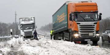 Dos camioneros se ayudan después de haber quedado atrapados por una fuerte nevada en la autopista A8 cerca de Holzkirchen, en el sur de Alemania, el lunes 7 de enero de 2019. Foto: Tobias Hase / dpa vía AP.