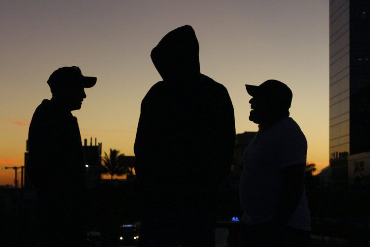 Fotografía del 16 de enero de 2019 de varios migrantes salvadoreños conversando poco antes de que partan hacia la frontera de México con Estados Unidos en una caravana desde San Salvador, El Salvador. (AP Foto/Salvador Meléndez)