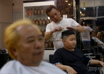 A Le Phuc Hai de 66 años, izquierda, y To Gia Huy, de 9 años, les cortan el cabello al estilo Trump y Kim en Hanoi, Vietnam, el martes 19 de febrero de 2019. Foto: Hau Dinh / AP.