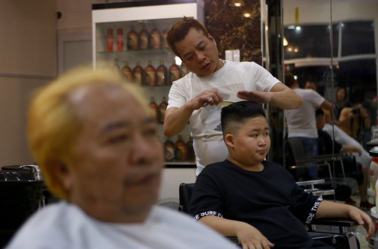 A Le Phuc Hai de 66 años, izquierda, y To Gia Huy, de 9 años, les cortan el cabello al estilo Trump y Kim en Hanoi, Vietnam, el martes 19 de febrero de 2019. Foto: Hau Dinh / AP.