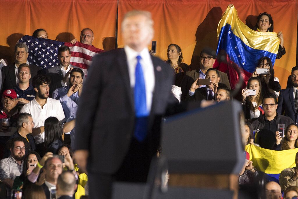 Personas de la audiencia ondean banderas de Venezuela y de Estados Unidos mientras el presidente Donald Trump habla ante la comunidad venezolana-estadounidense en el Centro Florida Ocean Bank Convocation de la Universidad Internacional de Florida el lunes 18 de febrero de 2019, en Miami. (AP Foto/Andrew Harnik)