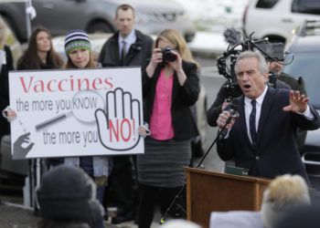 Robert Kennedy Jr., a la derecha, pronuncia un mensaje durante una manifestación en contra de una iniciativa que quitaría a los padres la autoridad de oponer razones filosóficas para impedir que a sus hijos en edad escolar les apliquen la vacuna combinada contra el sarampión, las paperas y la rubeola, afuera del Capitolio en Olympia, estado de Washington. El letrero dice: "Vacunas: ¡entre más sabes, más dices no!". (AP Foto/Ted S. Warren)