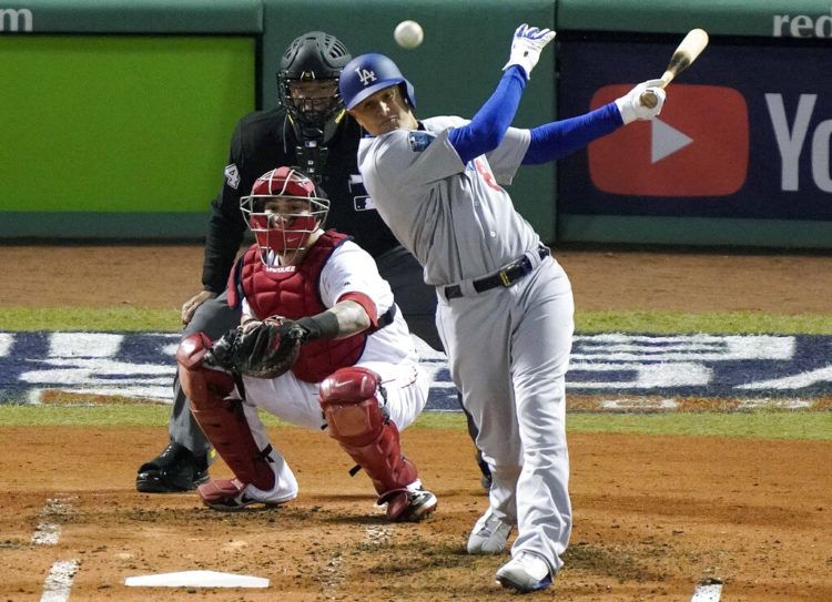 ARCHIVO - En esta foto del 24 de octubre de 2018, Manny Machado de los Dodgers de Los Ángeles Dodgers batea un sencillo frente al receptor Christian Vázquez de los Medias Rojas en el segundo juego de la Serie Mundial en Boston. (AP Foto/Elise Amendola, archivo)