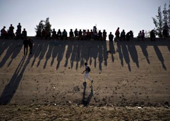 Migrantes cerca del paso fronterizo del Chaparral observan los enfrentamientos con la patrulla fronteriza de Estados Unidos, vistos desde Tijuana, México. (AP Foto/Ramón Espinosa, archivo)