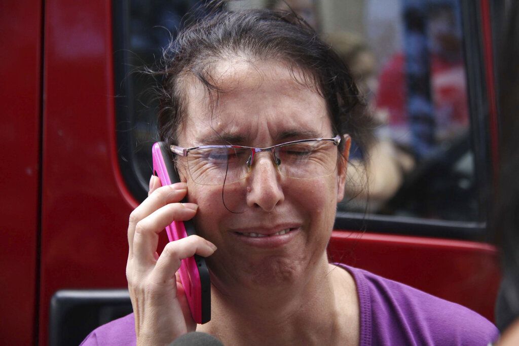 Una mujer usa su celular mientras espera por noticias en las afueras de la Escuela Estatal Raul Brasil en Suzano, Brasil, el miércoles, 13 de marzo del 2019. Dos adolescentes con capuchas abrieron fuego en una escuela pública el miércoles en el sur de Brasil, matando a seis personas antes de suicidarse, dijeron las autoridades. (Mauricio Sumiya/Futura Press via AP)