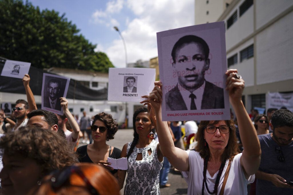 Un grupo de personas muestra fotografías de sus familiares asesinados durante la dictadura brasileña, en una protesta en el exterior de un recinto que fue centro de torturas en Sao Paulo, el sábado 30 de marzo de 2019. El gobierno de Jair Bolsonaro podrá seguir celebrando la última dictadura militar de Brasil, luego que una corte brasileña anulara una sentencia que prohibía realizar actos conmemorativos por el golpe militar que dio inicio a la dictadura brasileña en 1964. (AP Foto/Victor R. Caivano)