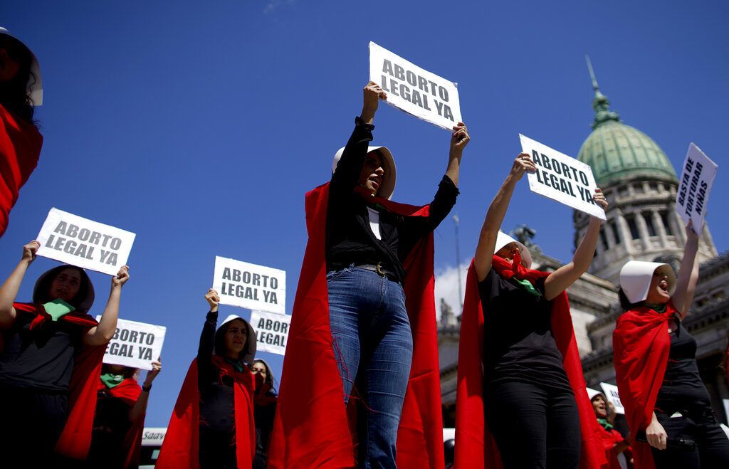 Activistas por el aborto libre vestidas como personajes de la novela convertida en serie de televisión "El cuento de la criada", sostienen pancartas en el Día Internacional de la Mujer en Buenos Aires, Argentina, el viernes 8 de marzo de 2018. Foto: Natacha Pisarenko / AP.