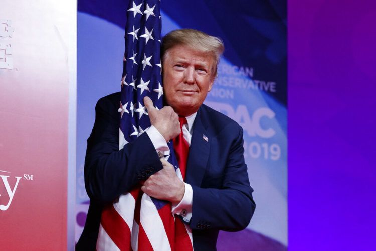 El presidente Donald Trump abraza la bandera estadounidense a su arribo a la Conferencia de Acción Política Conservadora en Oxon Hill, Maryland, donde pronunció un discurso de campaña en el que pronosticó su triunfo en 2020. Foto: Carolyn Kaster / AP.