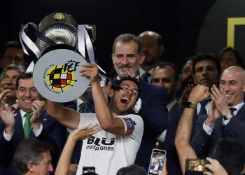 El capitán del Valencia CF, Daniel Parejo, levanta el trofeo, en presencia del rey Felipe y el presidente de la Junta de Andalucía, Juan Manuel Bonilla (i), tras vencer por 2-1 al FC Barcelona en la final de la Copa del Rey que ambos equipos han disputado esta noche en Estadio Benito Villamarín de Sevilla. EFE/Jose Manuel Vidal