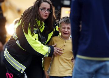 Una funcionaria guía a un alumno desde un autobús a un centro recreativo para ser reunido con sus padres después de un tiroteo en una escuela secundaria en los suburbios de Denver, el martes 7 de mayo de 2019, en Highlands Ranch, Colorado. Foto: David Zalubowski / AP.