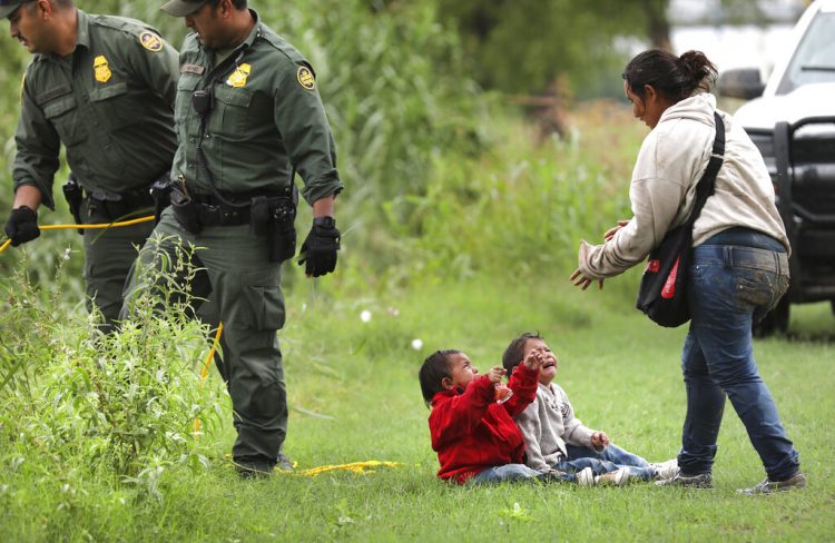 Una hondureña y sus dos hijos permanecen cerca de agentes de la Patrulla Fronteriza 10 de mayo de 2019 en el río Grande, cerca de Eagle Pass, en Texas, donde numerosas personas estaban cruzando a suelo estadounidense desde México en balsas. Foto: Bob Owen / The San Antonio Express-News vía AP.