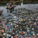 Un hombre conduce una balsa a través de un canal contaminado con bolsas de plástico y otros escombros en Mumbai, India, el 2 de octubre de 2016. Foto: Rafiq Maqbool / AP.