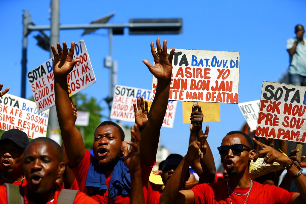 Manifestantes corean consignas contra el gobierno afuera del Buró Nacional de Seguros durante una manifestación del Primero de Mayo en Puerto Príncipe, Haití, el miércoles 1 de mayo de 2019. ( AP Foto/Dieu Nalio Chery)