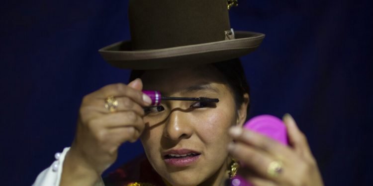 Una mujer aymara se maquilla mientras espera su turno para competir en el concurso Cholita Paceña 2019, en La Paz, Bolivia, el viernes 28 de junio de 2019. (AP Foto/Juan Karita)