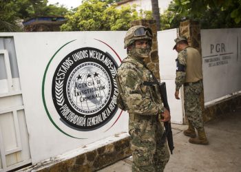 Un infante de Marina, al frente, y un miembro de la Guardia Nacional, atrás, vigilan afuera de una oficina de la Procuraduría General de la República adonde son enviados los migrantes antes de ser transferidos a Tapachula desde Arriaga, México, el domingo 23 de junio de 2019. Foto: Oliver de Ros / AP.