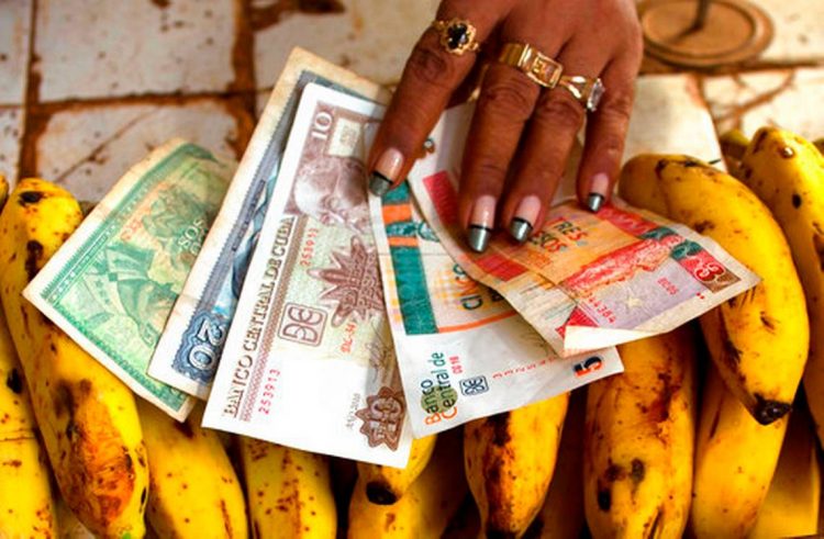 En esta foto de archivo una vendedora de alimentos distribuye pesos convertibles y pesos cubanos en su puesto en un mercado de verduras en La Habana, Cuba. Foto: AP/Ramón Espinosa.