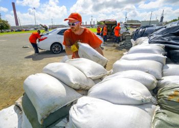 Trabajadores reclusos del departamento de policía de la municipalidad de St. Bernard trasladan costales de arena para los residentes en Chalmette, Luisiana, el jueves 11 de julio de 2019. Foto: Matthew Hinton / AP.