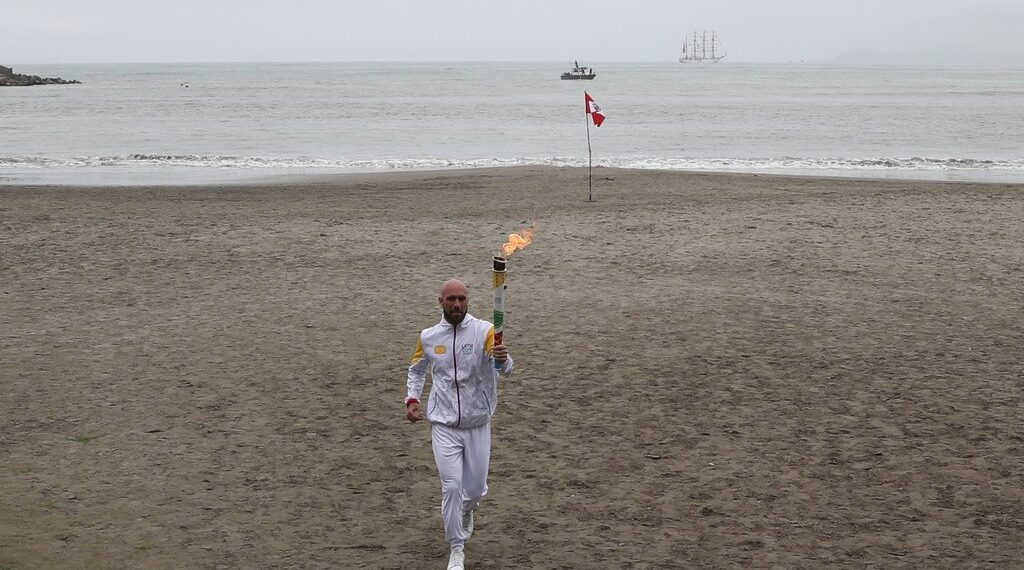 El extenista peruano Luis Horna corre con la antorcha de los Juegos Panamericanos en la playa Los Yuyos de Lima, el viernes 26 dejulio de 2019, horas antes de la ceremonia inaugural (AP Foto/Martín Mejía)