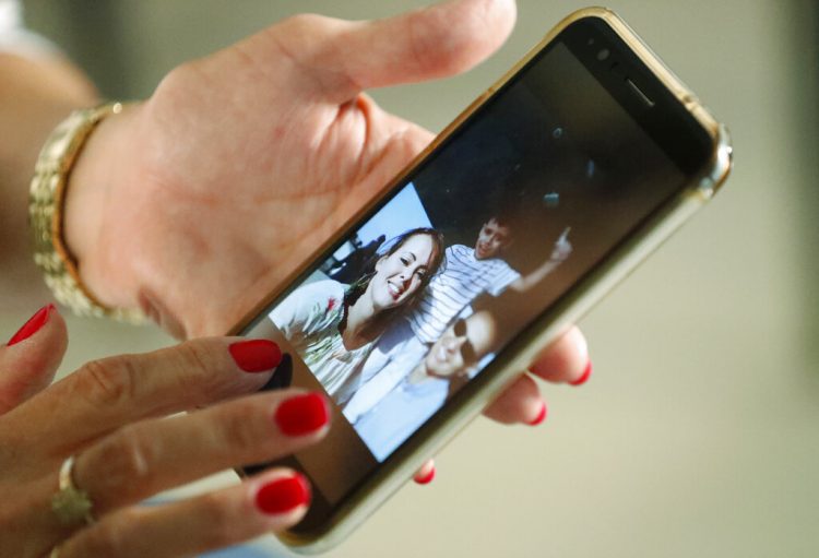 Mary Sardinas, de 60 años, muestra una fotografía de su hijo, su nuera y su nieto en Cuba. Su sueño de reunirse con sus familiares han quedado en suspenso desde septiembre de 2017, cuando el gobierno de Donald Trump retiró a gran parte del personal de la embajada de La Habana. Foto: Wilfredo Lee/AP.