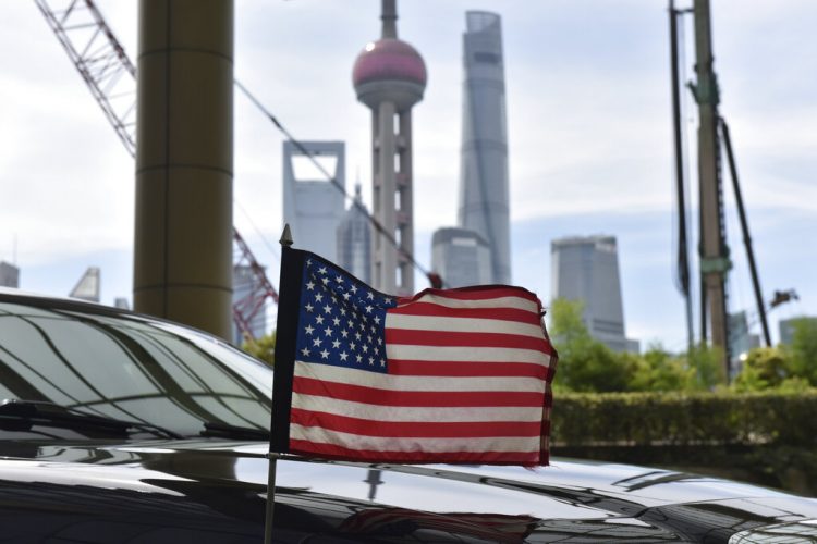 Una bandera de Estados Unidos ondea en un auto del consulado, delante de los edificios del distrito financiero de Lujiazui, en el exterior del hotel donde se alojan los negociadores comerciales de EEUU durante los contactos con sus homólogos chinos, en Shanghái, el 31 de julio de 2019. Foto: Greg Baker/Pool vía AP.