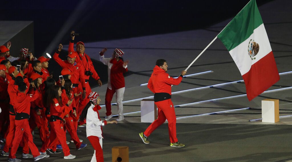 El tirador mexicano Jorge Orozco porta la bandera de su país en la ceremonia inaugural de los Juegos Panamericanos de Lima, el viernes 26 de julio de 2019 (AP Foto/Silvia Izquierdo)