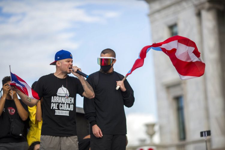 Los artistas puertorriqueños René Pérez “Residente” y Benito Antonio Martinez Ocasio “Bad Bunny” avivan a la gente previo a una manifestación frente al capitolio puertorriqueño contra el gobernador Ricardo Roselló, en San Juan, Puerto Rico, el miércoles 17 de julio de 2019. Foto: Dennis Rivera/AP.