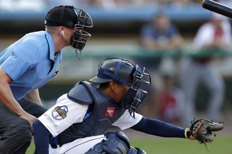 El árbitro del plato Brian deBrauwere, se coloca detrás del catcher James Skelton, del Revolution de York, durante el Juego de Estrellas de la Liga del Atlántico, el miércoles 10 de julio de 2019. Foto: Julio Cortez / EFE.