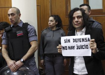 Cristian Aldana, vocalista principal de la banda de rock argentina El Otro Yo, posa durante su juicio por presunto abuso sexual de menores con un cartel que dice "Sin defensa no hay juicio" el viernes 12 de julio del 2019 en Buenos Aires. Foto: Bernardino Avila/ AP.