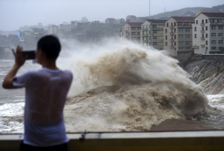 Un hombre graba con su celular el fuerte oleaje causado por la cercanía del tifón Lekima, en la ciudad de Wenling, en el la provincia oriental china de Zhejiang. (Han Chuanhao/Xinhua vía AP)