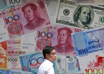 Un hombre camina frente a una casa de cambio decorada con distintos billetes en el distrito financiero de Hong Kong. (AP Foto/Kin Cheung, Archivo)