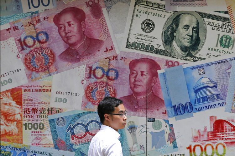 Un hombre camina frente a una casa de cambio decorada con distintos billetes en el distrito financiero de Hong Kong. (AP Foto/Kin Cheung, Archivo)