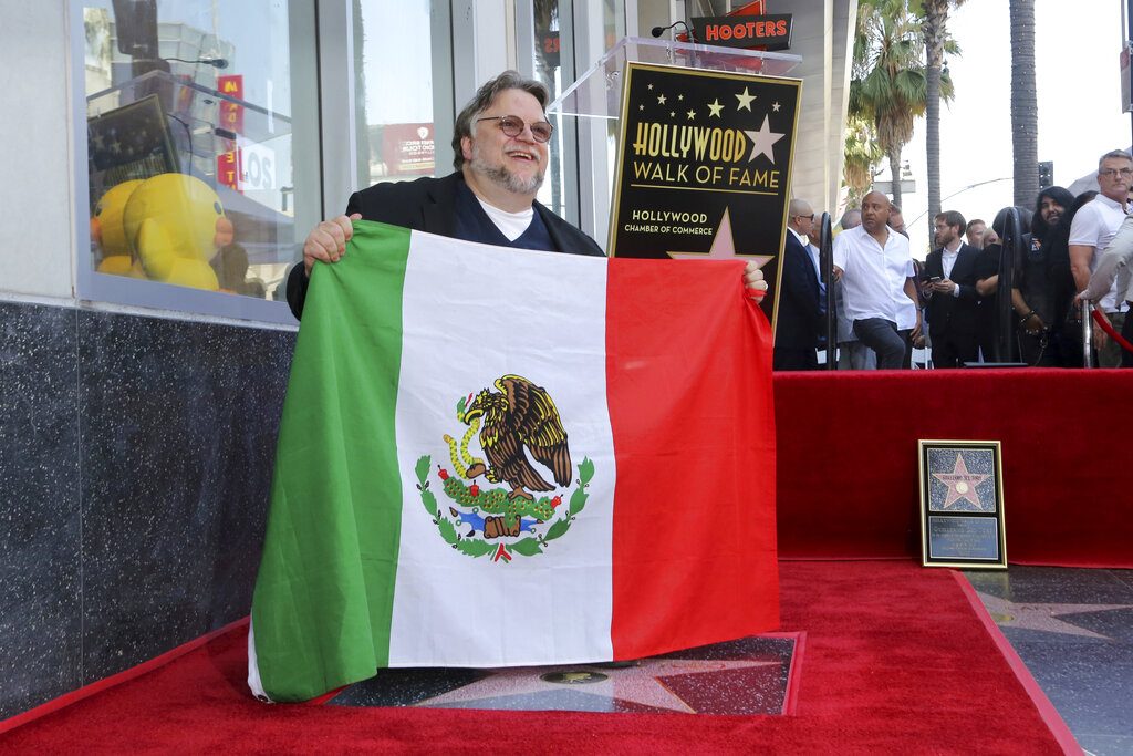 El cineasta mexicano Guillermo del Toro posa con la bandera de México tras una ceremonia en su honor para develar su estrella en el Paseo de la Fama de Hollywood el martes 6 de agosto de 2019 en Los Angeles. Foto: Willy Sanjuan/Invision/AP.