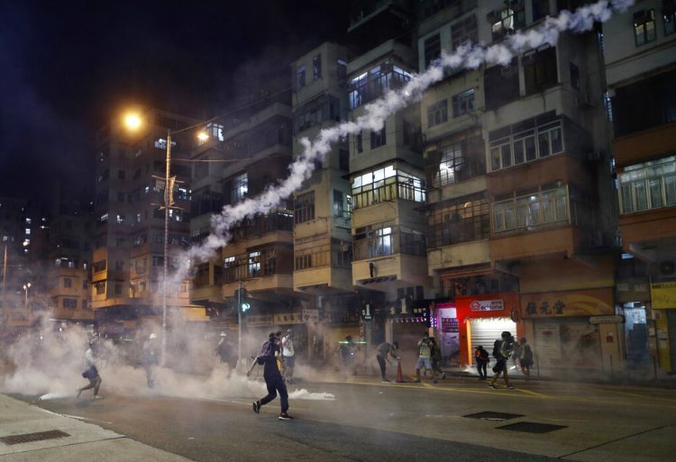 Unos manifestantes caminan en medio de gases lacrimógenos lanzados por la policía en Hong Kong el miércoles 14 de agosto del 2019. Foto: Vincent Yu / AP.