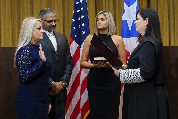 La secretaria de Justicia Wanda Vázquez es juramentada como gobernadora de Puerto Rico por la magistrada del Tribunal Superior Maite Oronoz, en San Juan, Puerto Rico, el miércoles 7 de agosto de 2019. A Vázquez la acompañan su hija Beatriz Díaz Vázquez y su esposo, el juez Jorge Díaz. (AP Foto/Dennis M. Rivera Pichardo)