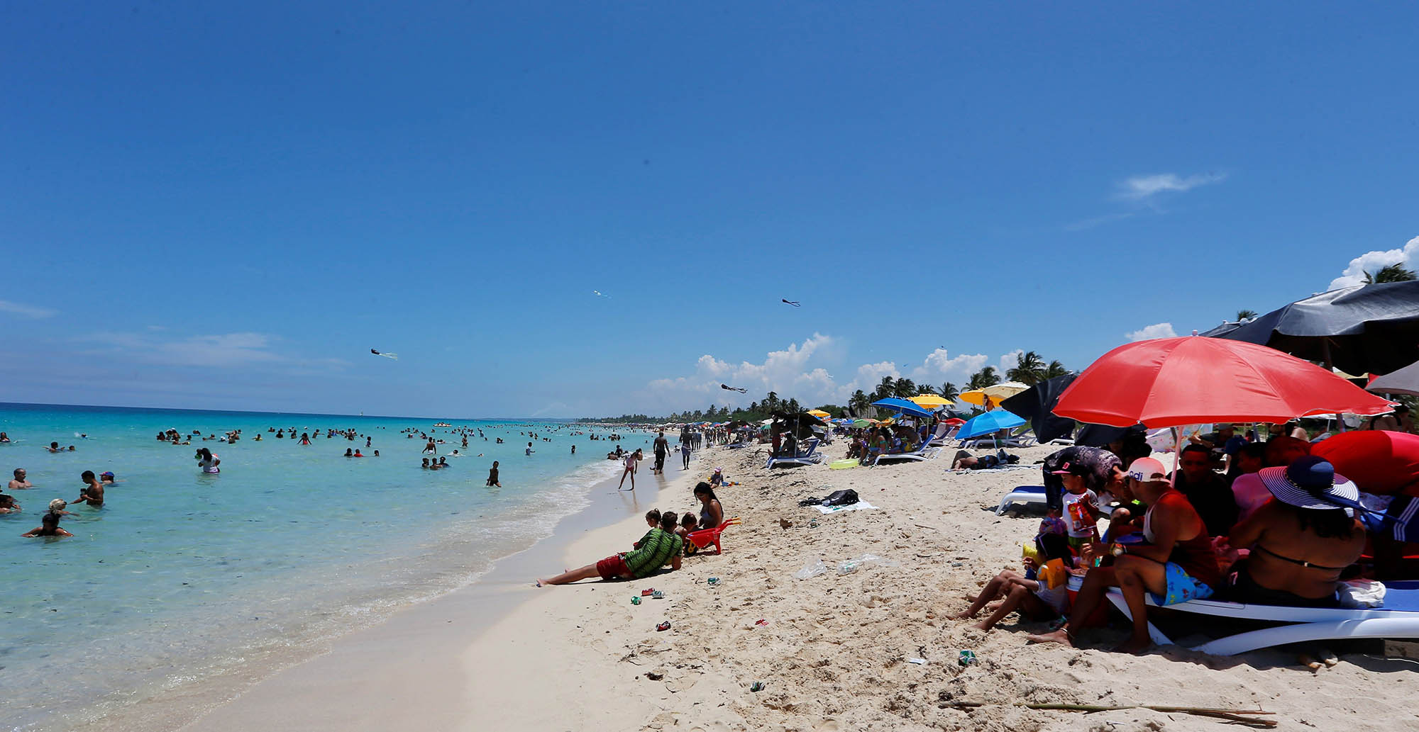 "Los muchos", se meten todos debajo de las sombrillas para huirle un poco al sol. Foto: Ernesto Mastrascusa / EFE.